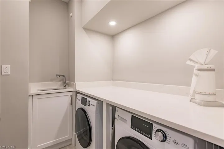 Clothes washing area with sink and separate washer and dryer