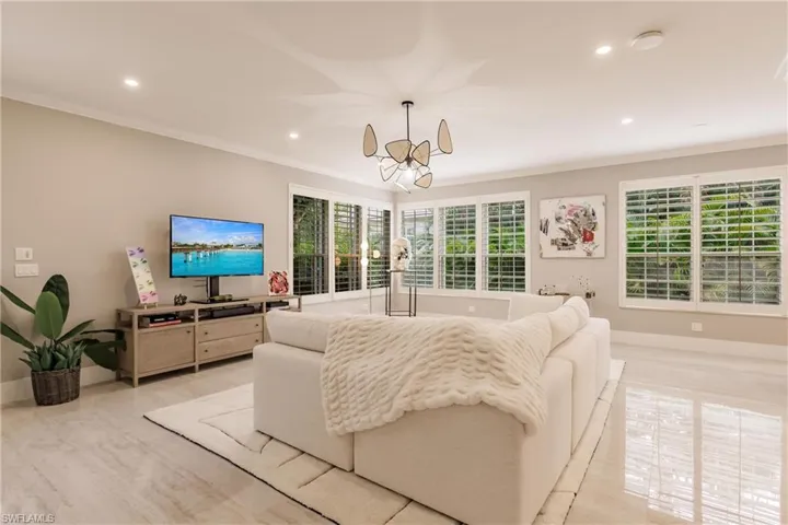 Living room with ornamental molding and a notable chandelier