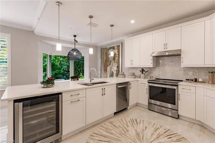 Kitchen featuring beverage cooler, stainless steel appliances, sink, kitchen peninsula, and white cabinets
