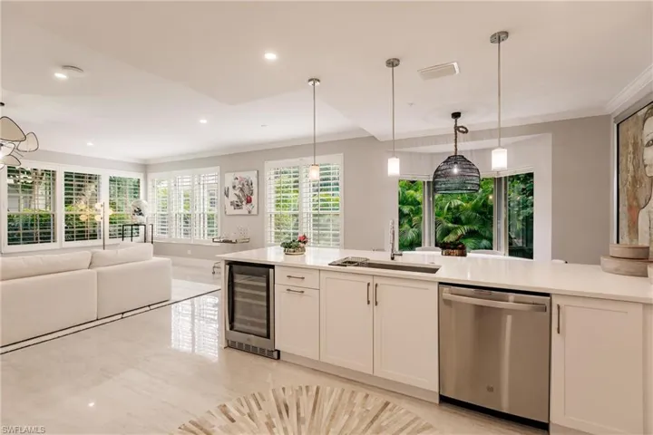 Kitchen with beverage cooler, stainless steel dishwasher, sink, and hanging light fixtures