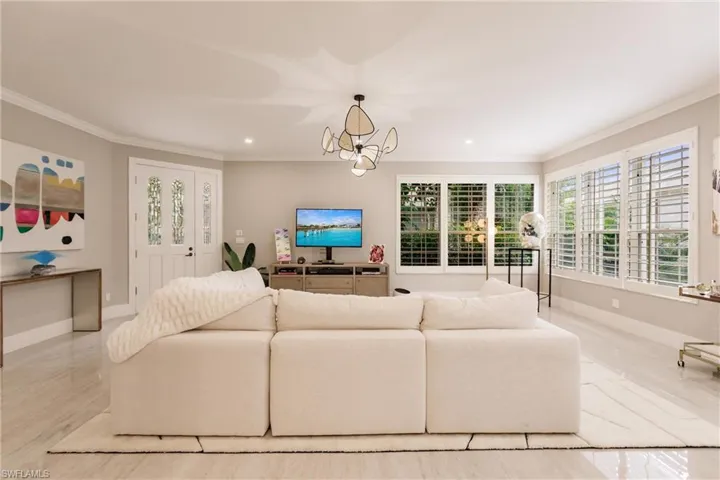 Living room featuring crown molding and a notable chandelier