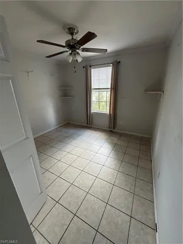 Spare room with light tile patterned flooring, a ceiling fan, and ornamental molding