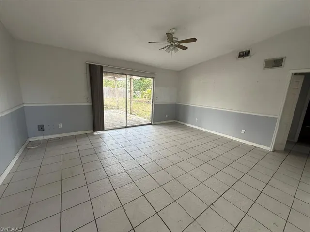 Spare room featuring lofted ceiling, ceiling fan, and light tile patterned flooring