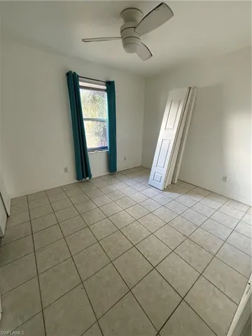 Unfurnished room with light tile patterned floors and ceiling fan