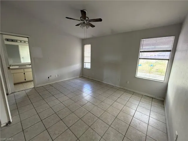 Unfurnished room featuring a ceiling fan, light tile patterned floors, and lofted ceiling