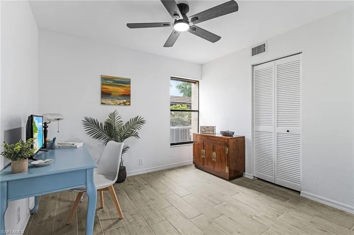 Office space featuring wood tiled floor, baseboards, ceiling fan, and visible vents