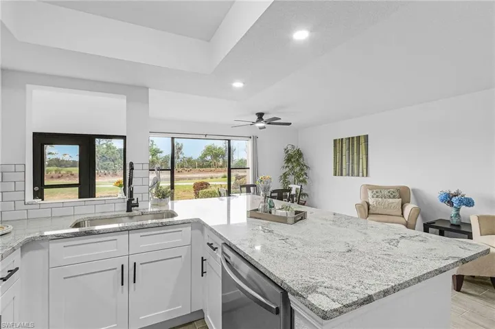 Kitchen with ceiling fan, stainless steel dishwasher, a sink, light stone counters, and recessed lighting