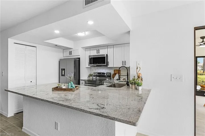 Kitchen featuring decorative backsplash, visible vents, appliances with stainless steel finishes, a sink, and a peninsula