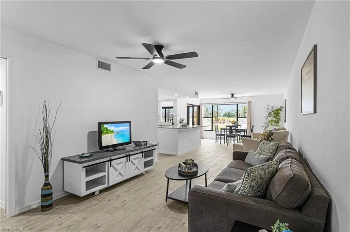 Living room with a ceiling fan, baseboards, visible vents, and light wood-type flooring