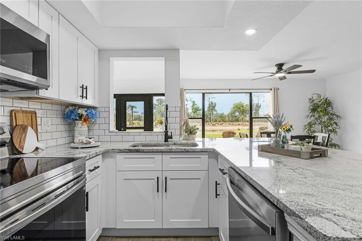 Kitchen featuring tasteful backsplash, a ceiling fan, stainless steel appliances, and light stone countertops