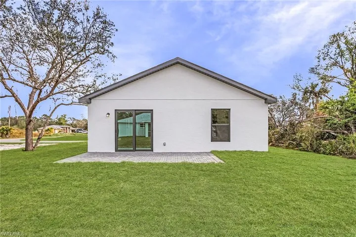 Back of property with a lawn, a patio, and stucco siding