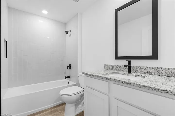 Bathroom featuring wood finished floors, vanity, and shower / bath combination