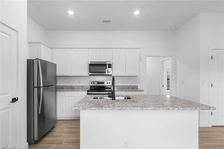 Kitchen featuring stainless steel appliances, light wood finished floors, white cabinets, and recessed lighting