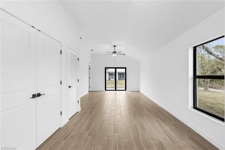 Unfurnished room with a ceiling fan, lofted ceiling, and light wood-style flooring