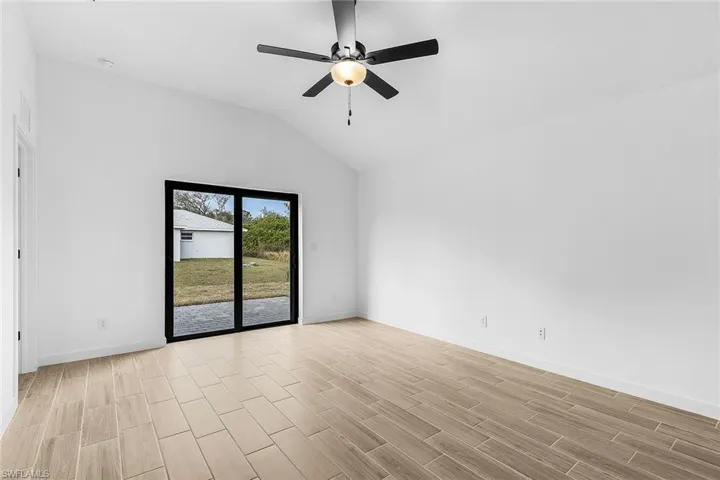 Empty room featuring wood tiled floors, a ceiling fan, and vaulted ceiling