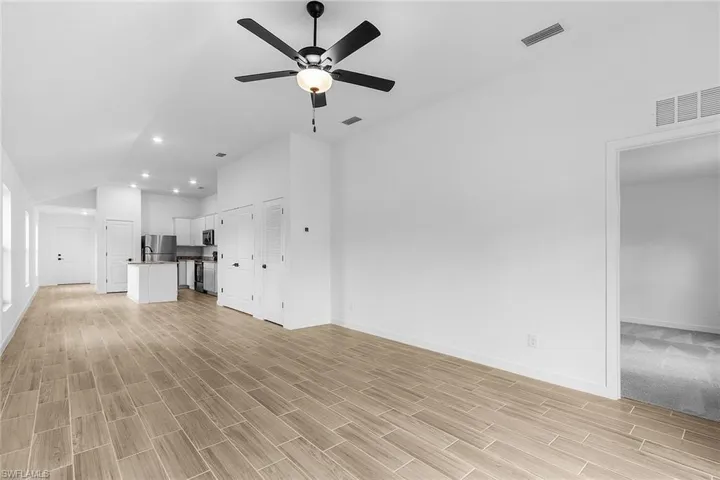 Unfurnished living room with lofted ceiling, a ceiling fan, light wood finished floors, and recessed lighting