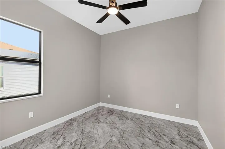 Empty room with marble look tiles and a ceiling fan