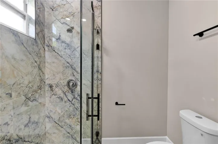Bathroom with a marble finish shower and toilet