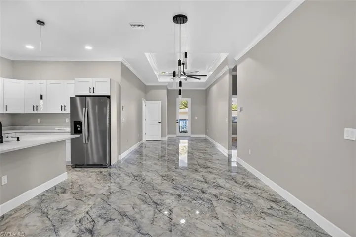 Kitchen featuring stainless steel fridge with ice dispenser, white cabinets, ceiling fan, ornamental molding, and decorative light fixtures