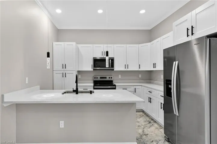 Kitchen with stainless steel appliances, light marble finish floors, ornamental molding, light stone countertops, and white cabinetry