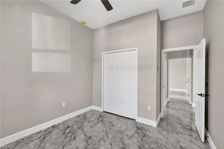 Unfurnished bedroom with light marble finish flooring, a closet, and a ceiling fan