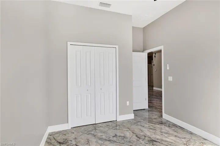 Unfurnished bedroom with light marble finish flooring and a closet