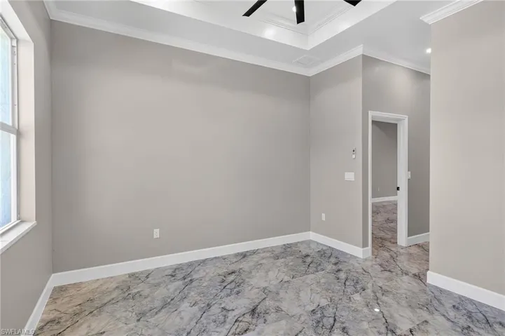 Spare room with light marble finish floors, ornamental molding, ceiling fan, and plenty of natural light
