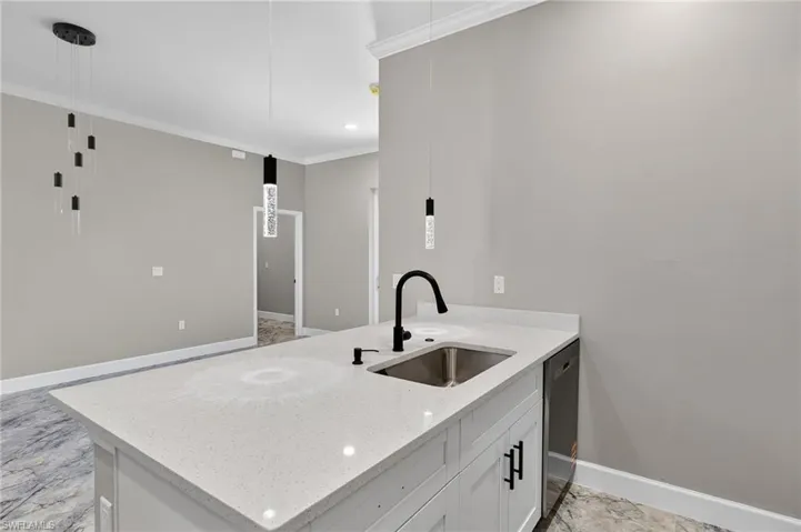 Kitchen featuring decorative light fixtures, light stone counters, ornamental molding, a peninsula, and dishwasher