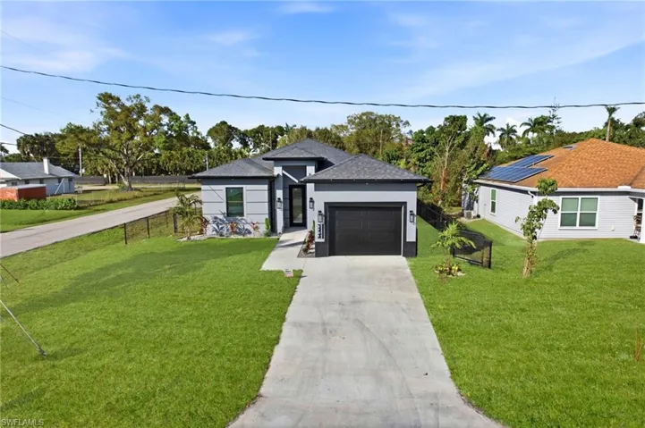View of front facade with driveway, a front lawn, a garage, and stucco siding
