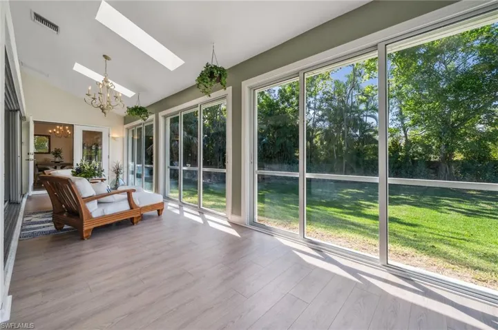 Unfurnished sunroom with a chandelier, vaulted ceiling with skylight, and visible vents