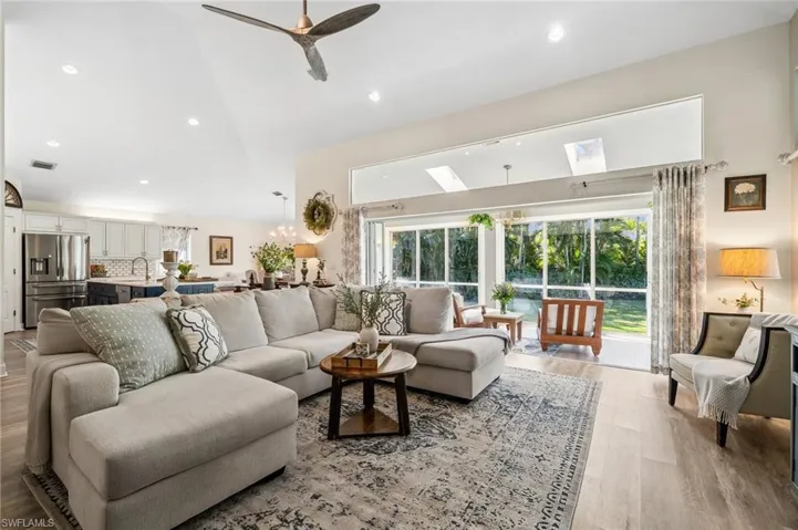 Living area featuring visible vents, ceiling fan with notable chandelier, vaulted ceiling, light wood-type flooring, and recessed lighting