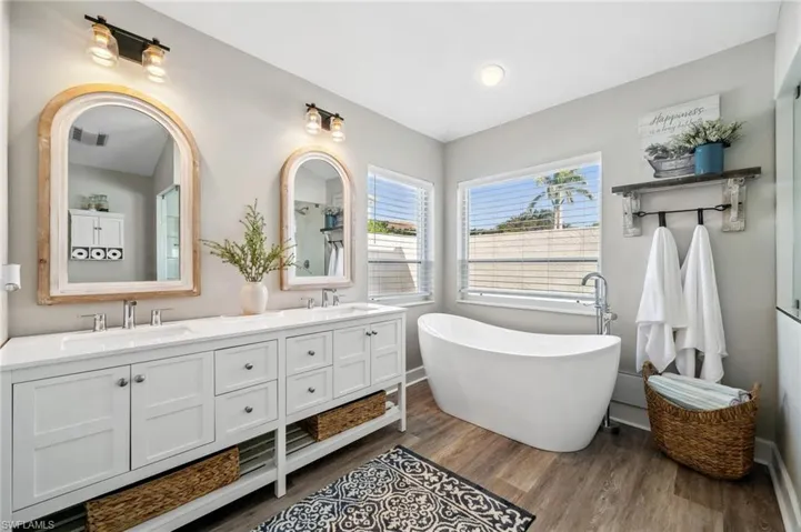 Full bath featuring visible vents, a sink, a freestanding bath, and wood finished floors