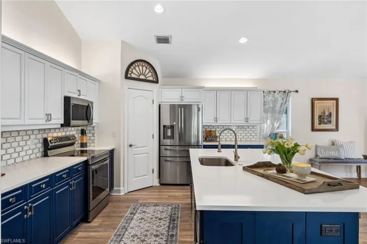 Kitchen featuring blue cabinetry, visible vents, appliances with stainless steel finishes, a sink, and wood finished floors