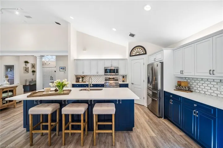 Kitchen featuring decorative columns, stainless steel appliances, a sink, blue cabinets, and a kitchen bar