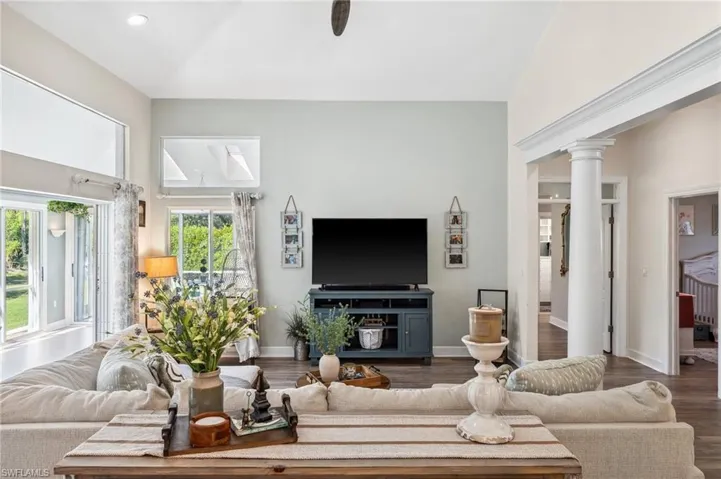 Living area with wood finished floors, decorative columns, and baseboards