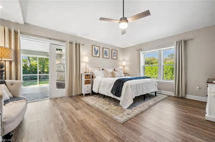 Bedroom featuring access to exterior, a ceiling fan, vaulted ceiling, wood finished floors, and baseboards