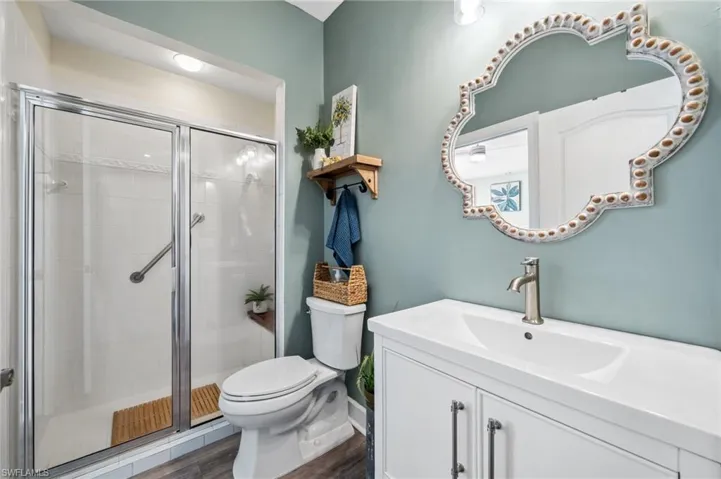 Bathroom with a stall shower, vanity, toilet, and wood finished floors