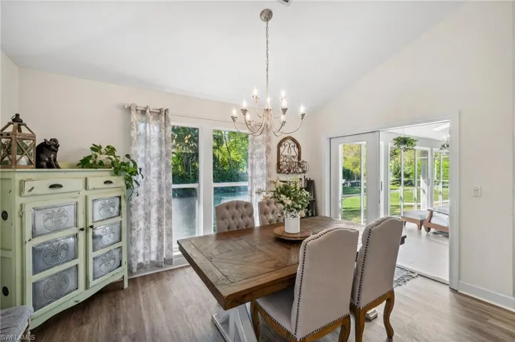 Dining space with vaulted ceiling, baseboards, wood finished floors, and an inviting chandelier