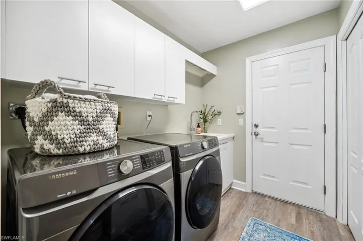Laundry area with a sink, cabinet space, light wood finished floors, and washer and dryer