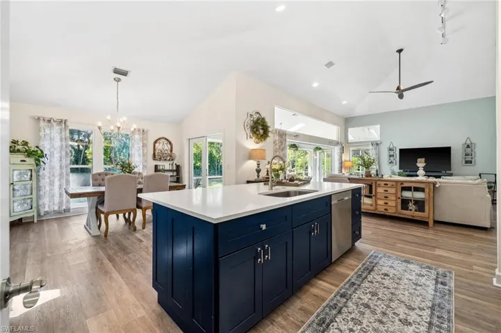 Kitchen with blue cabinetry, light countertops, stainless steel dishwasher, open floor plan, and a sink