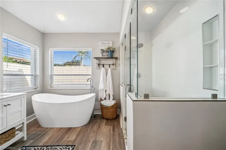 Full bathroom with a freestanding bath, wood finished floors, vanity, and a shower stall