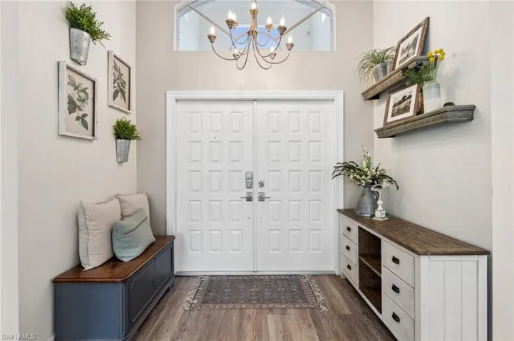 Entrance foyer with dark wood-style floors and an inviting chandelier