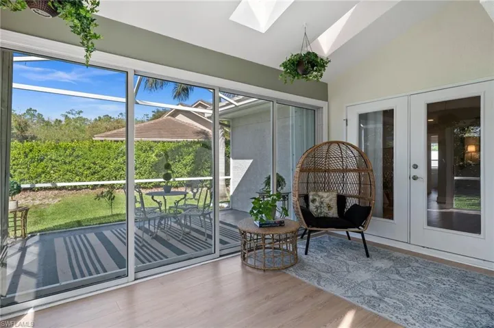 Unfurnished sunroom with vaulted ceiling with skylight and french doors