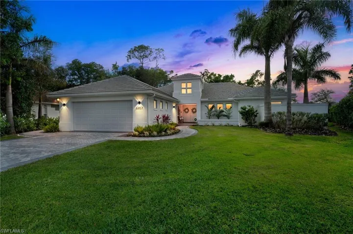 View of front facade with decorative driveway, stucco siding, a lawn, an attached garage, and a tiled roof