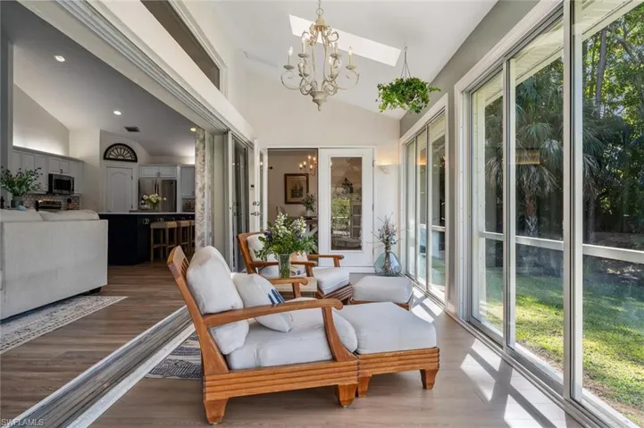 Sunroom with lofted ceiling with skylight and a notable chandelier