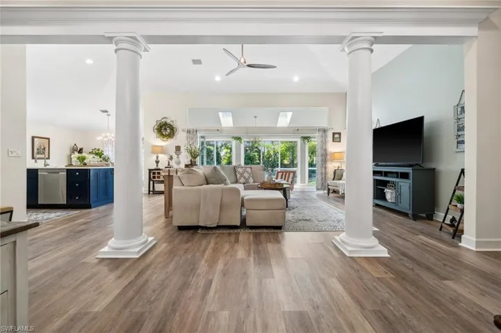 Living area with recessed lighting, wood finished floors, decorative columns, and baseboards