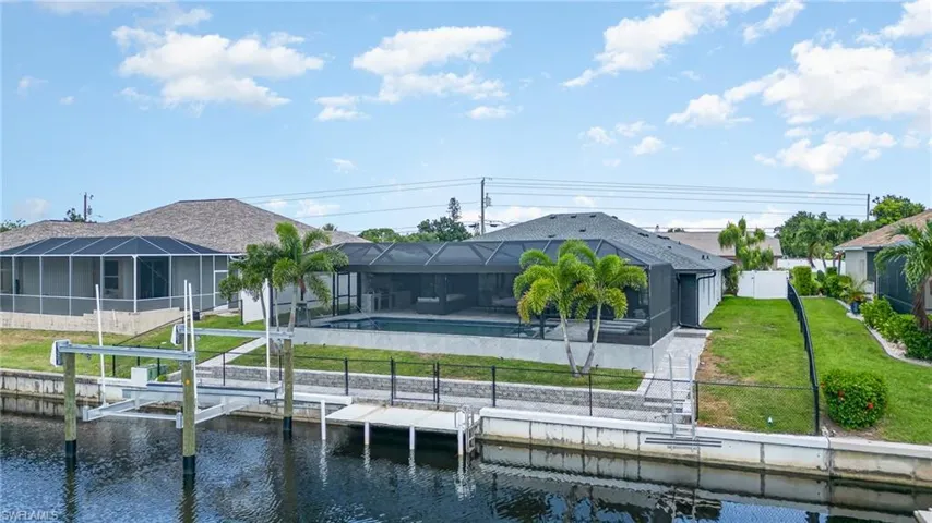 Rear view of property with a lanai, a yard, and water view