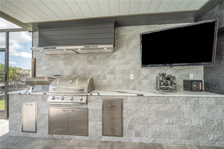 Canal & pool view featuring a grill and outdoor kitchen