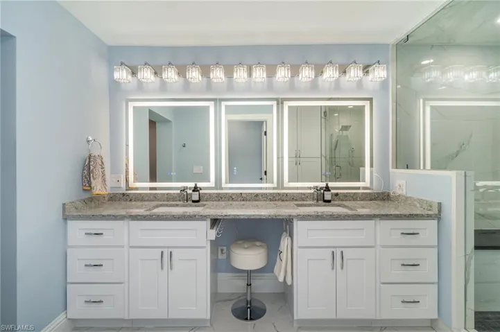 Dual sinks, quartz counters, seating/makeup area between sinks, quartz, marble flooring.