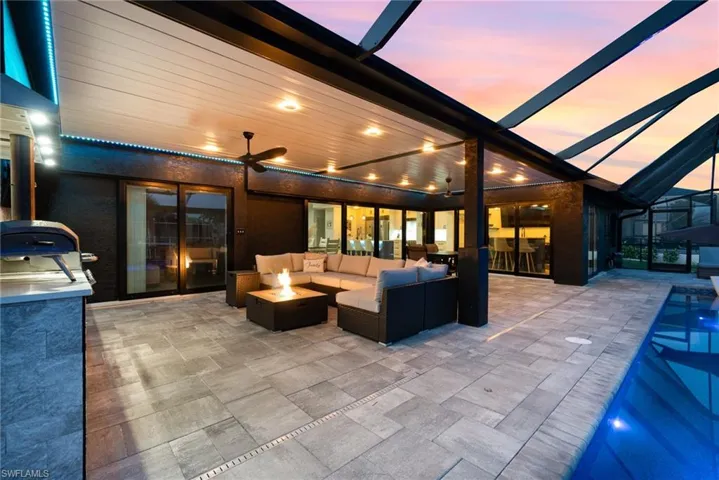Screened Lanai at dusk with area for grilling, an outdoor living space, and heated pool